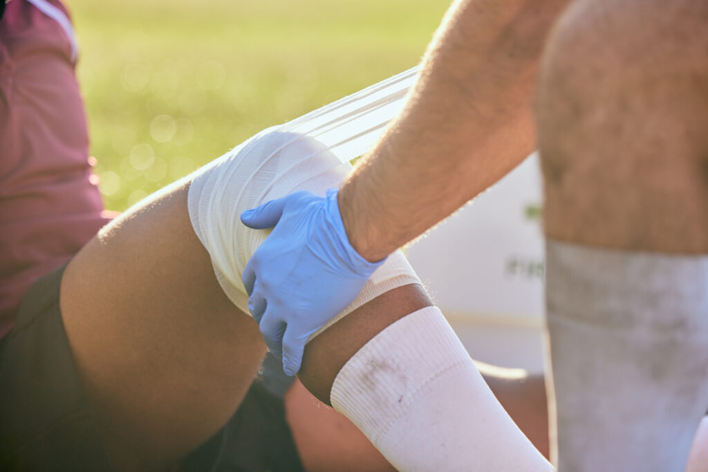 applying-bandage-to-leg-on-green-field-2026-01-09-11-42-41-utc